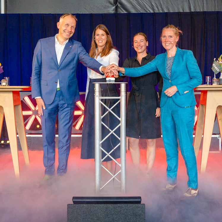 Een viertal werknemers van Eneco drukken gezamenlijk een grote rode startknop in