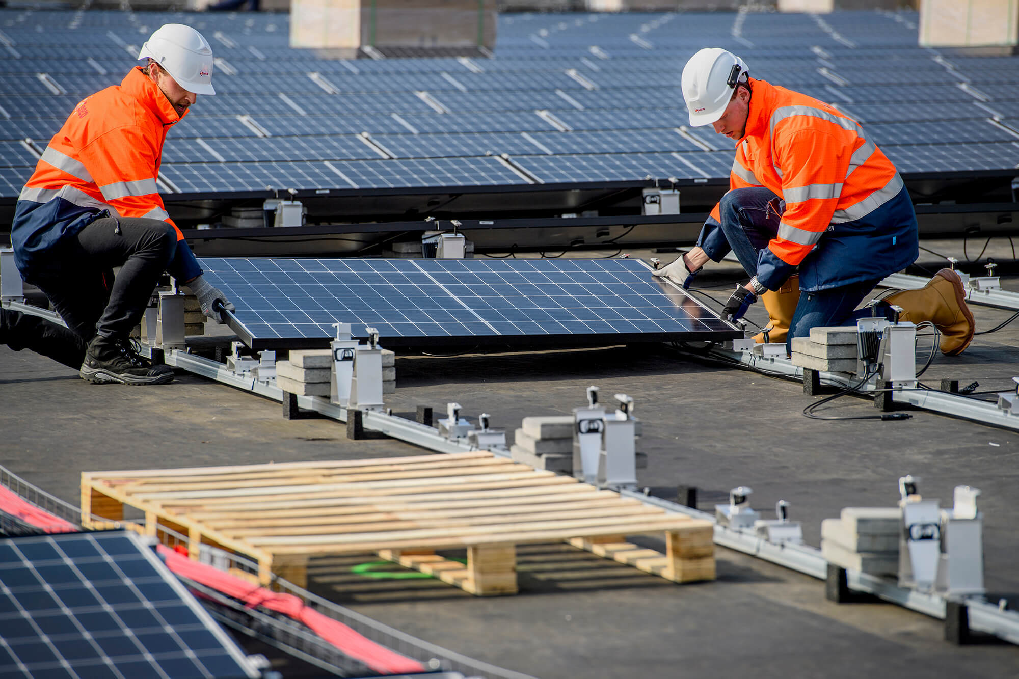 Twee Eneco medewerkers plaatsen een zonnepaneel op het dak van Kingspan