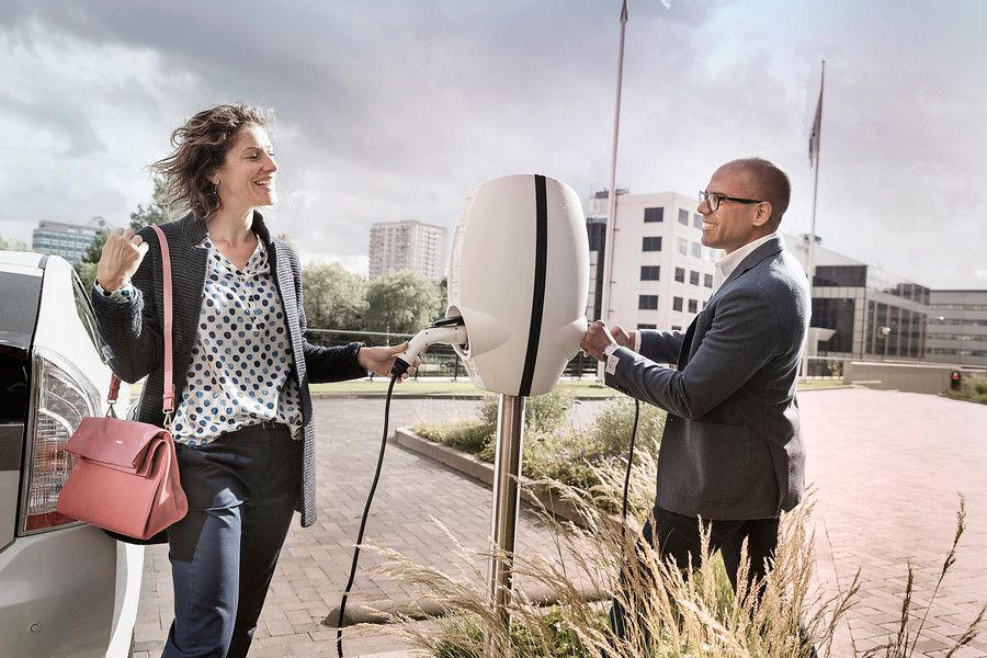 Een man en een vrouw bij een elektrische laadpaal