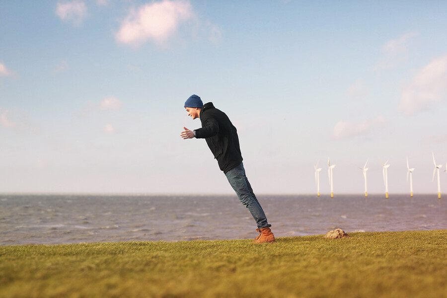 Man tegen de wind in met windmolens op achtergrond