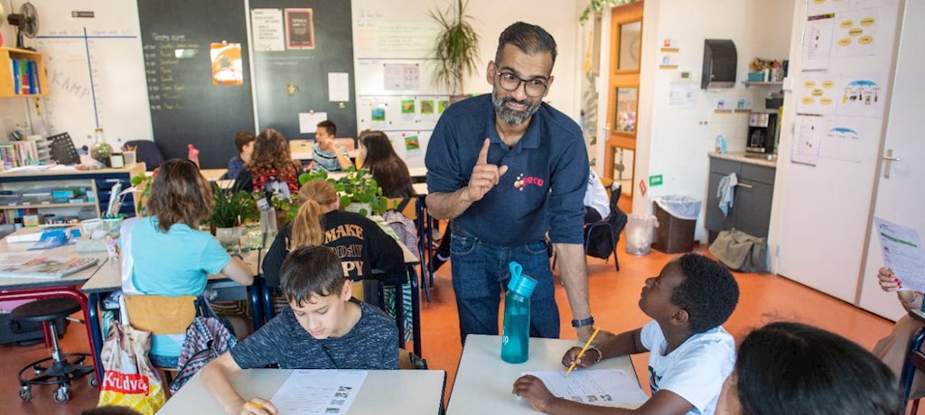 Ewald Gobind, custom engineer bij Eneco, staat in een klaslokaal op de basisschool en geeft een gastles over duurzame energie
