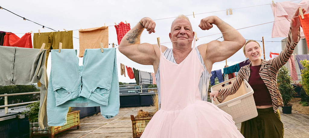 vrouw hangt was op en man laat spierballen zien voor een tutu