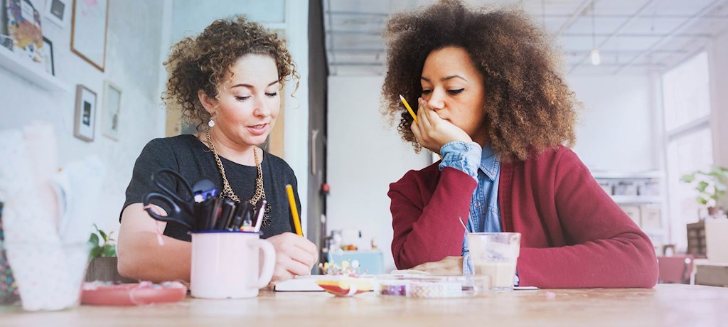 Meiden aan tafel gebogen over papierwerk