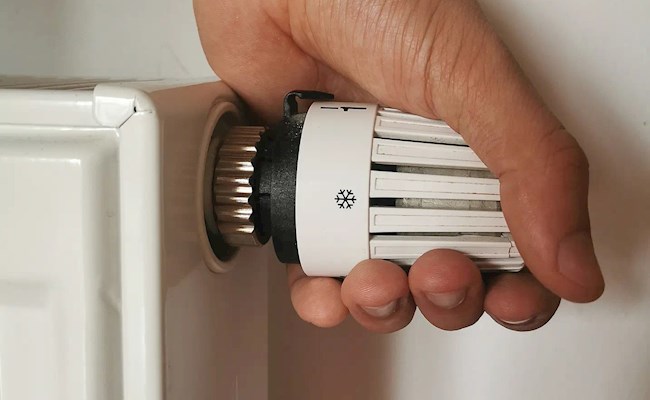 Een hand draait aan de radiatorknop