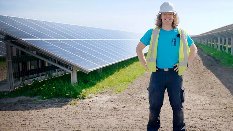 Man met helm staat tussen de zonnepanelen