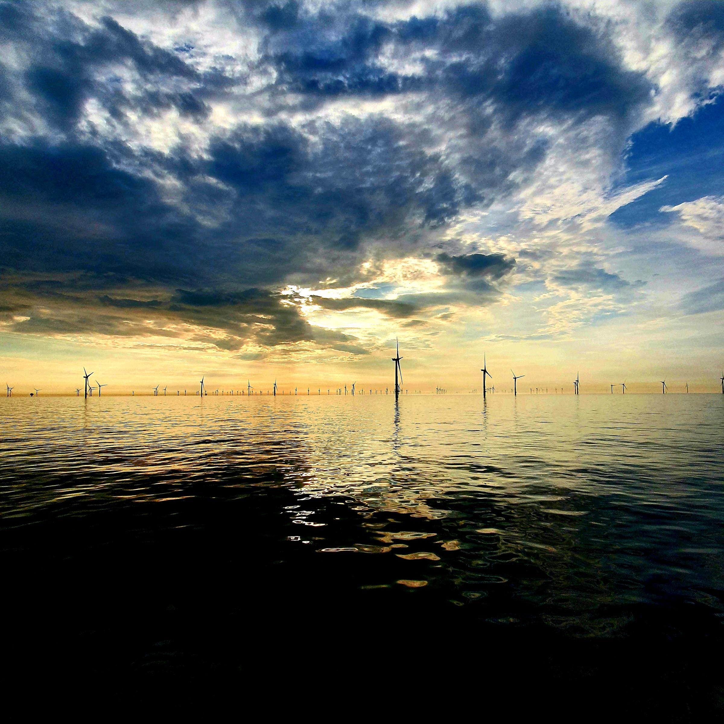 Windmolenpark op zee tijdens zonsondergang