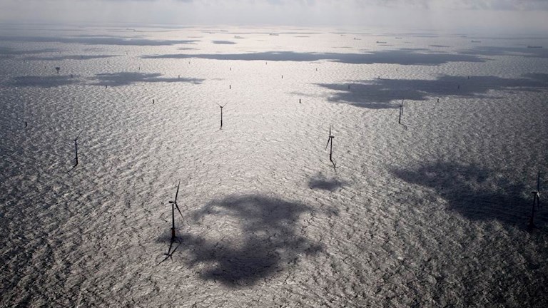 Windmolens op zee met schaduwen van wolken op het water