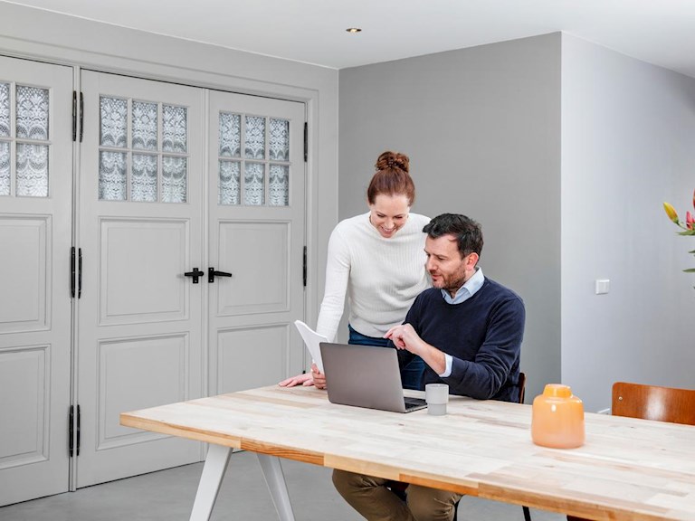Een meneer en mevrouw kijken samen op de laptop. 