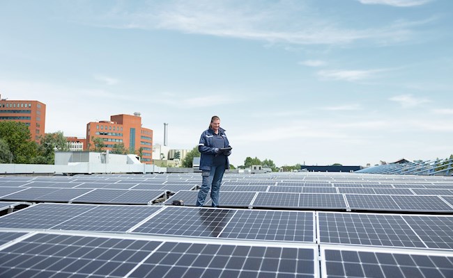 Eneco monteur staat bovenop een dak met zonnepanelen