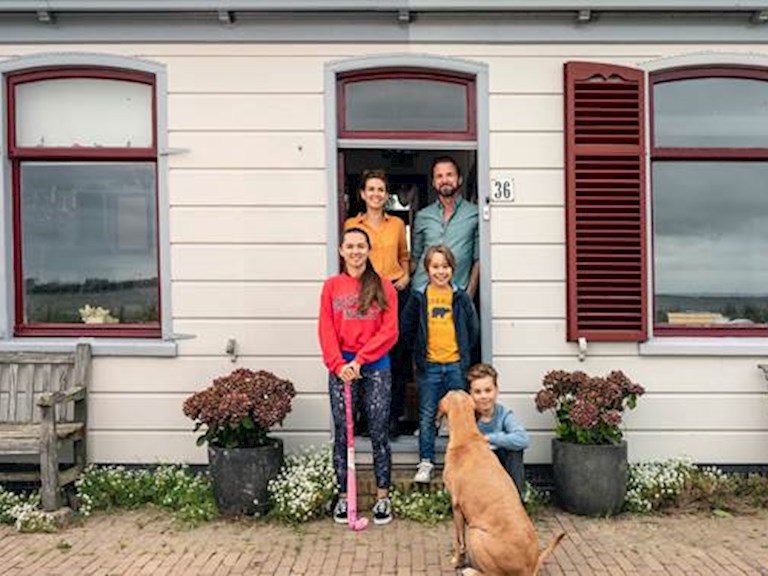 Gezin met hond staat in de deuropening van hun woning