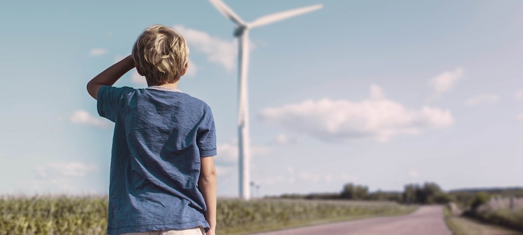Verwachting energietarieven, jongen kijkt naar windmolen