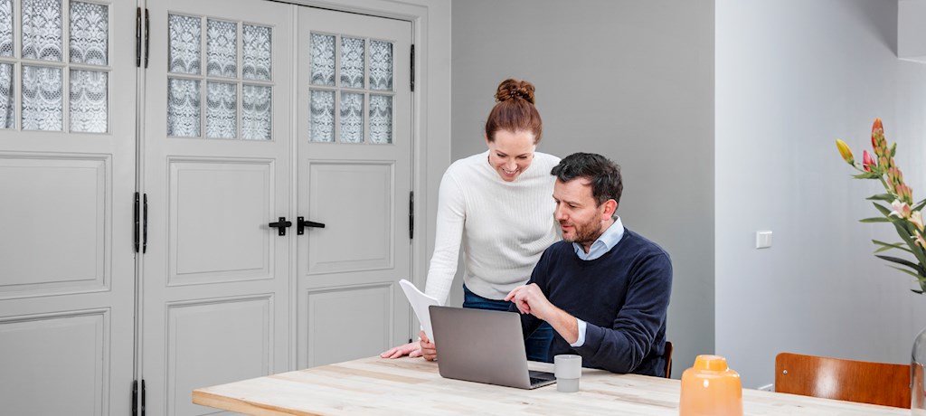 Koppel bekijkt energierekening achter laptop