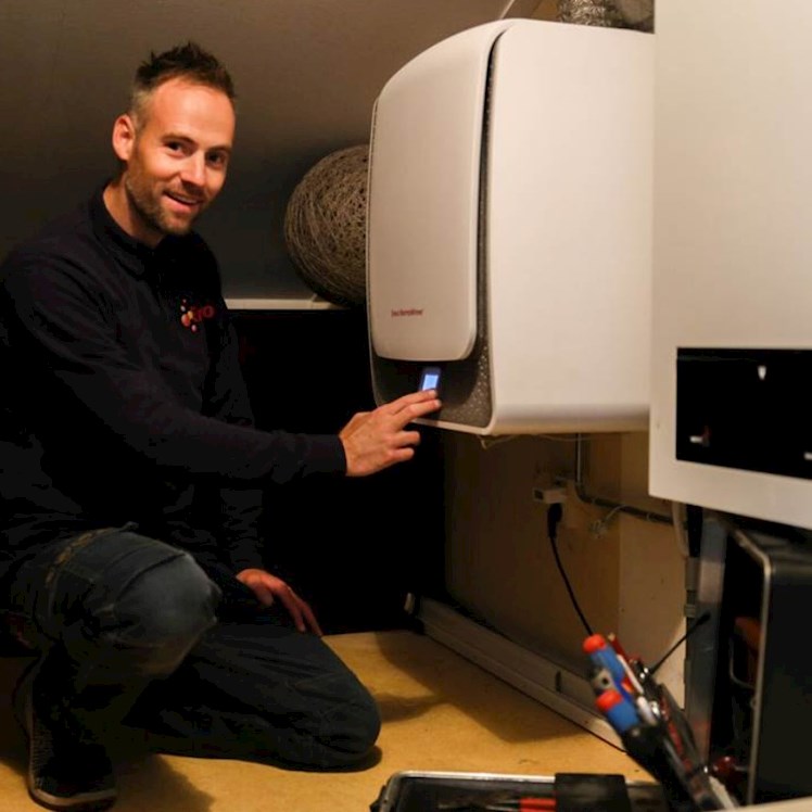 Monteur op zolder met een warmtepomp en cv-ketel