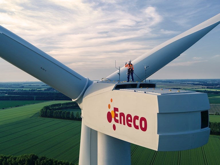 Monteur staat boven op een Eneco windmolen en steekt zijn duim op