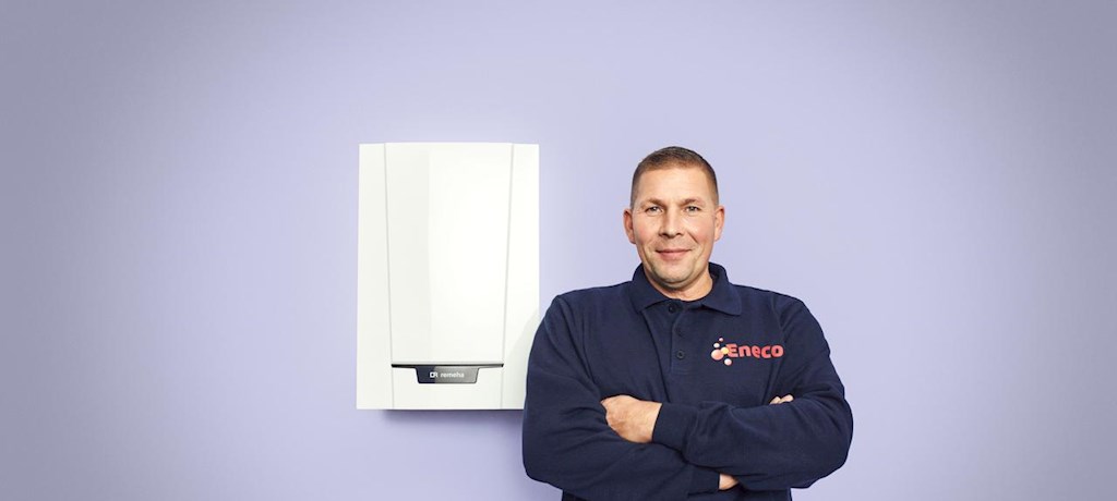 Een monteur van Eneco staat trots naast een cv-ketel.