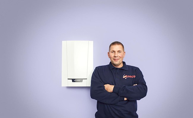 Een monteur van Eneco staat trots naast een cv-ketel.
