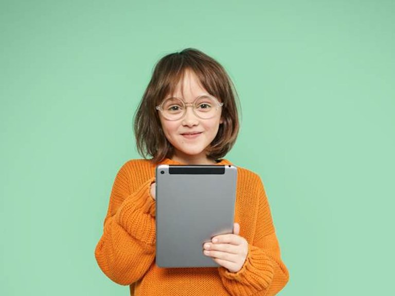Meisje met bril in oranje trui houdt een laptop vast