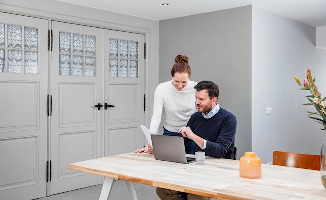 Een stel kijkt samen naar bespaartips op de laptop
