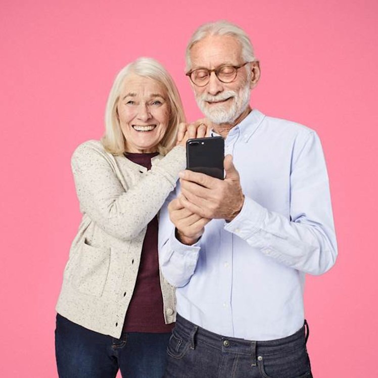 Lachend ouder echtpaar met mobiele telefoon in hun hand