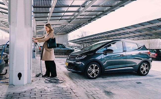 Vrouw sluit haar auto aan op een elektrische laadpaal