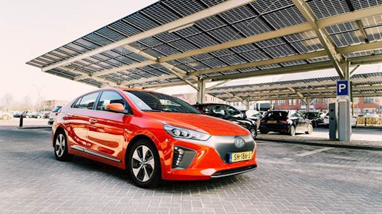 Rode auto onder een carport met zonnepanelen