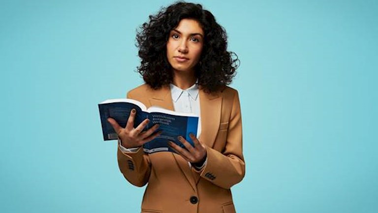Vrouw met wetboek in haar handen voor een blauwe achtergrond