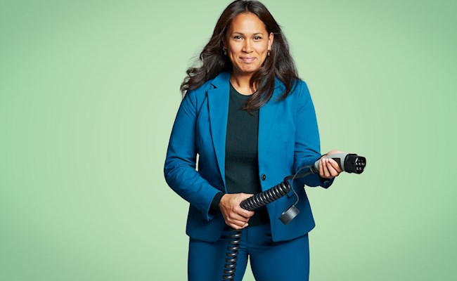 Mevrouw houdt een stekker vast om haar auto elektrisch te laden