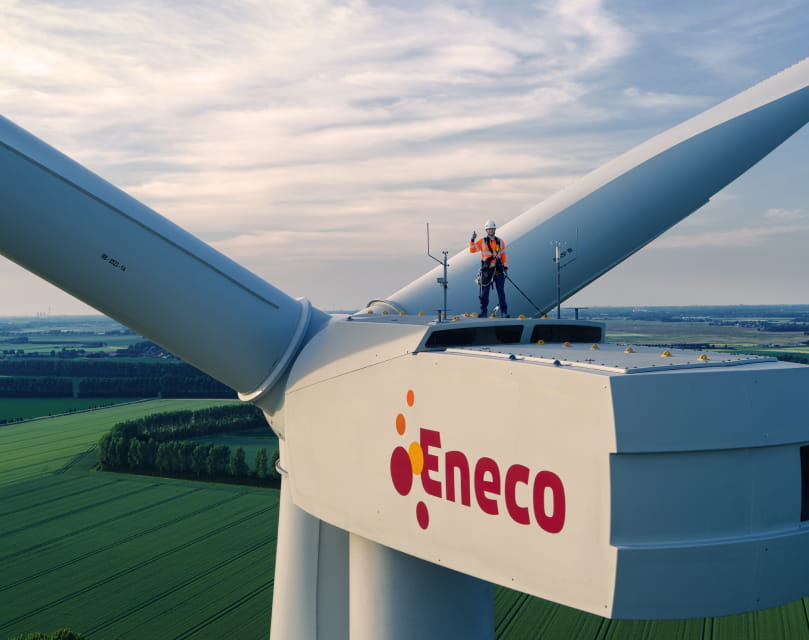 Een monteur staat op een Eneco windmolen