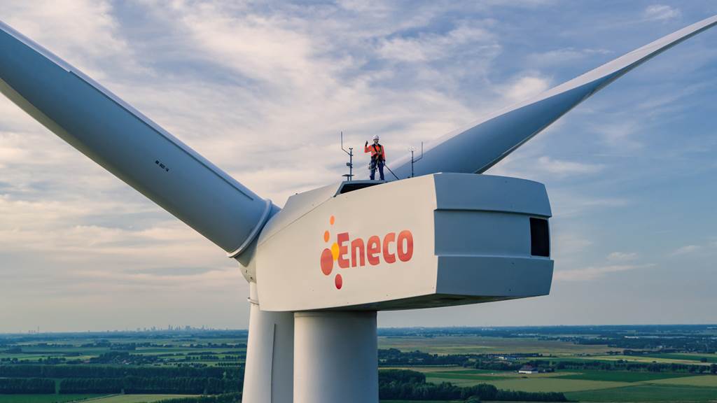 Een Eneco monteur staat op een windmolen en zorgt voor goed onderhoud.