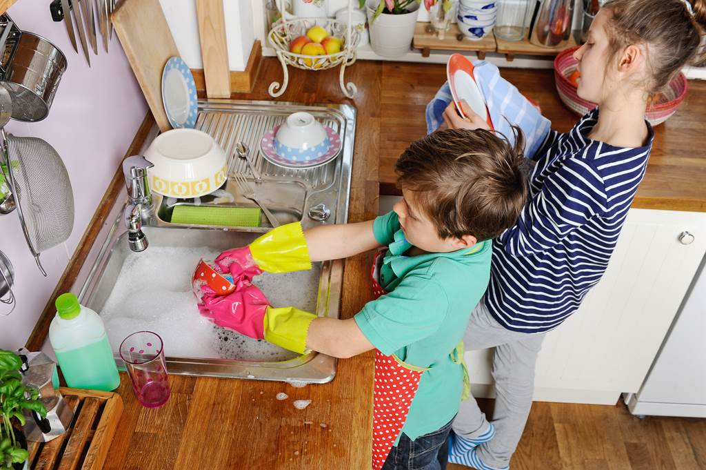Twee kinderen wassen af in de keuken