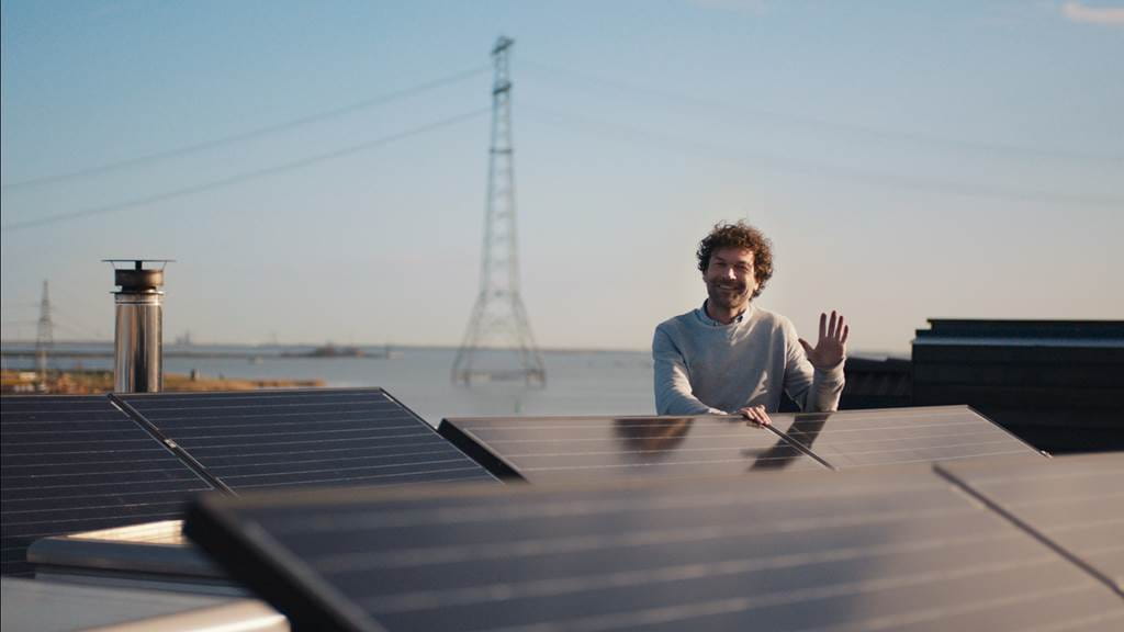 man bij zonnepanelen op dak